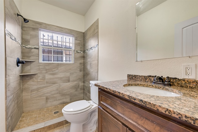 bathroom featuring tiled shower, tile patterned flooring, vanity, and toilet