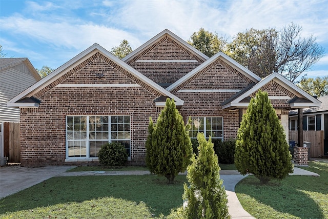 view of front of house with fence, a front lawn, and brick siding