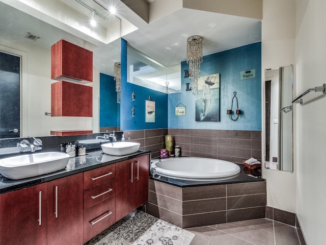 bathroom featuring tile patterned flooring, vanity, and a relaxing tiled tub