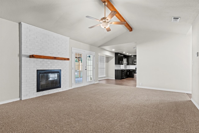 unfurnished living room featuring french doors, dark colored carpet, vaulted ceiling with beams, and a fireplace