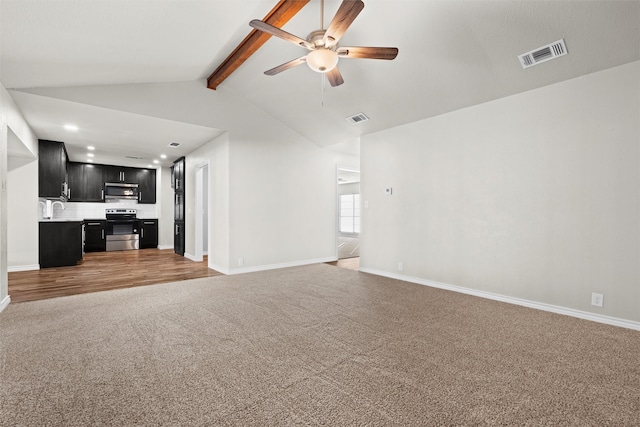 unfurnished living room with ceiling fan, carpet, sink, and vaulted ceiling with beams