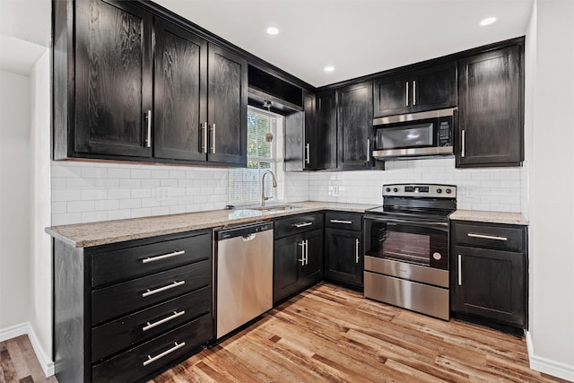 kitchen featuring stainless steel appliances, light stone countertops, sink, and light wood-type flooring