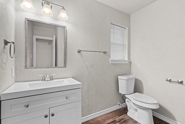 bathroom with wood-type flooring, vanity, and toilet