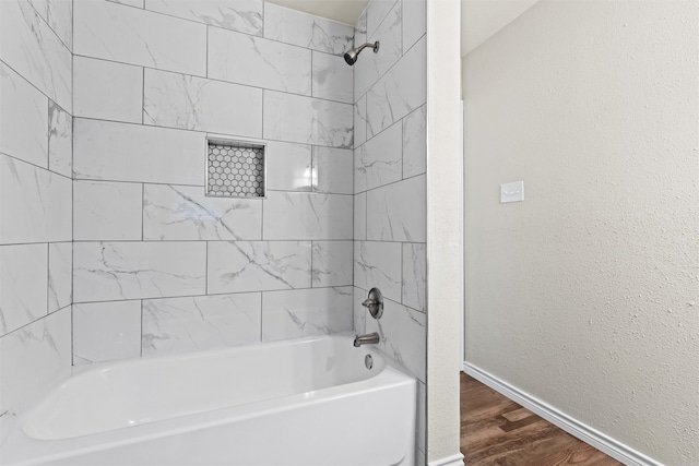 bathroom featuring wood-type flooring and tiled shower / bath