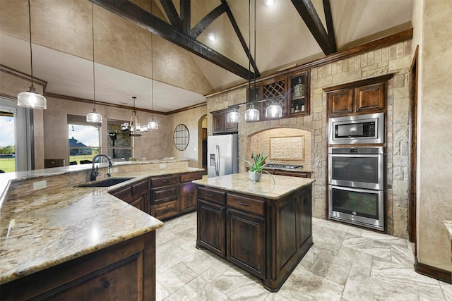 kitchen featuring sink, hanging light fixtures, stainless steel appliances, light stone countertops, and a spacious island