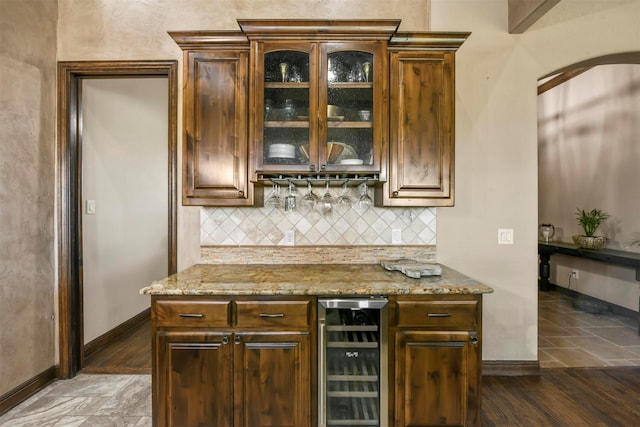 kitchen with dark hardwood / wood-style flooring, backsplash, light stone countertops, and beverage cooler