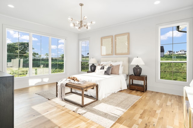 bedroom featuring ornamental molding, light hardwood / wood-style flooring, and a chandelier