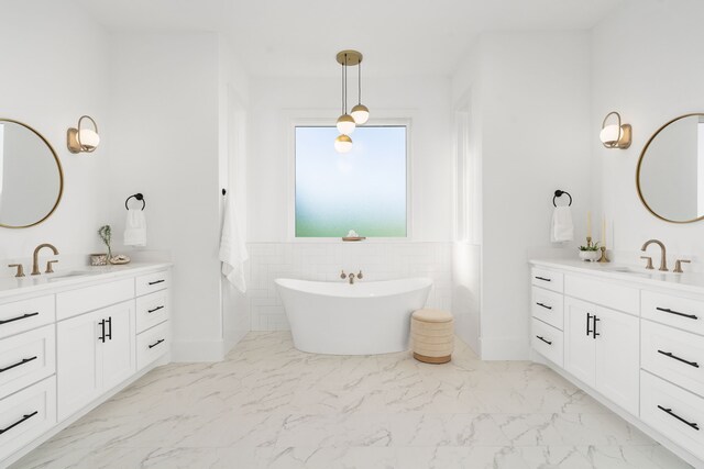 7745 Laura Lake Ln, Fort Worth, TX 76126 - bathroom featuring marble finish floors, two vanities, a freestanding bath, a wainscoted wall, and tile walls