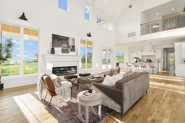 living room with high vaulted ceiling, light hardwood / wood-style floors, and a healthy amount of sunlight