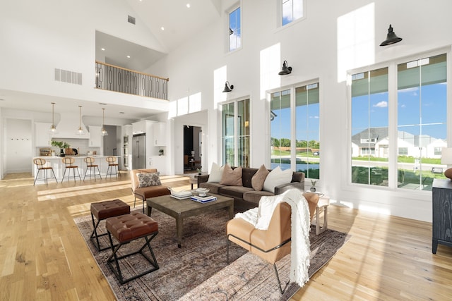 living room with high vaulted ceiling and light hardwood / wood-style floors