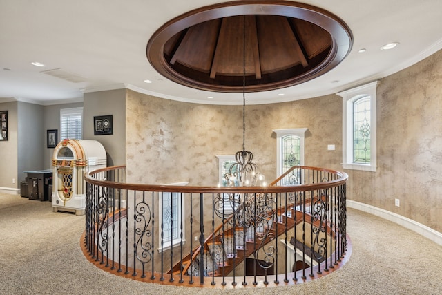 hallway featuring a notable chandelier, carpet floors, crown molding, and a tray ceiling