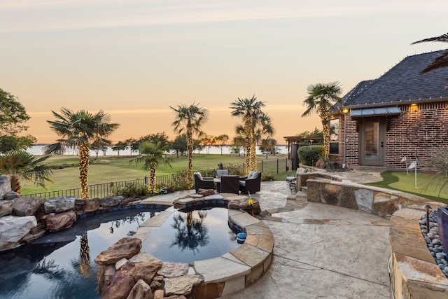 patio terrace at dusk with a swimming pool with hot tub