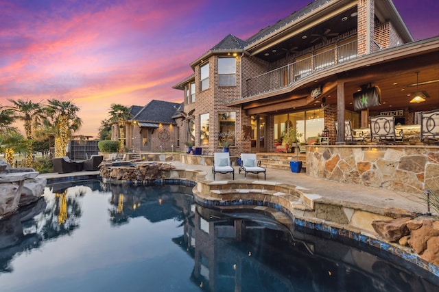 pool at dusk with a patio area, an in ground hot tub, and ceiling fan