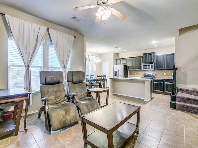 living room featuring ceiling fan with notable chandelier, light tile patterned flooring, and sink