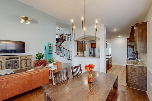 dining room with light hardwood / wood-style floors and ceiling fan with notable chandelier