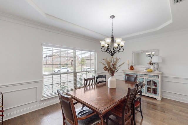 dining room with crown molding, hardwood / wood-style floors, a chandelier, and a raised ceiling