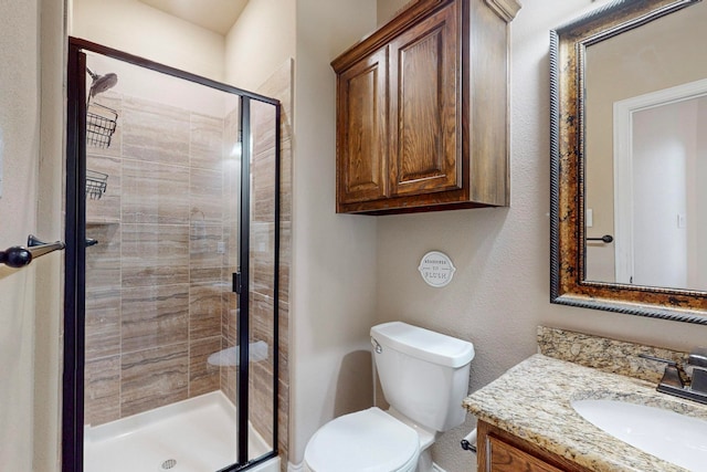 bathroom featuring vanity, toilet, and a shower with door