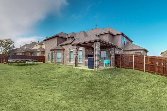 back of house with a patio, a lawn, and a trampoline