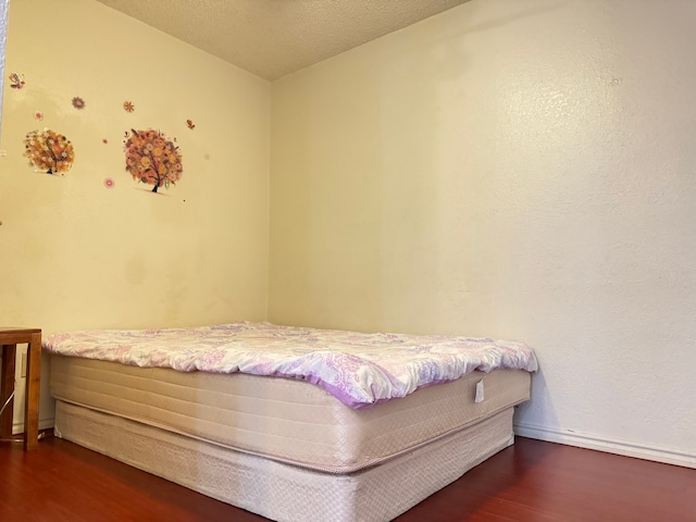 unfurnished bedroom featuring dark hardwood / wood-style flooring and a textured ceiling