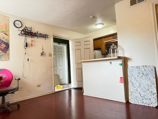 kitchen featuring dark wood-type flooring, kitchen peninsula, white refrigerator, and a textured ceiling