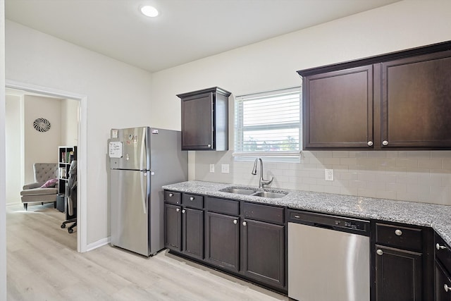 kitchen with light hardwood / wood-style floors, stainless steel appliances, light stone counters, sink, and dark brown cabinets