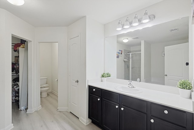 bathroom with walk in shower, vanity, hardwood / wood-style floors, and toilet