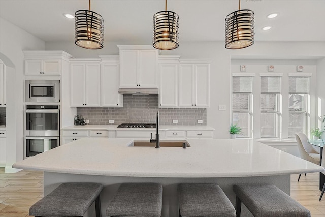 kitchen featuring decorative light fixtures, white cabinetry, sink, and stainless steel appliances