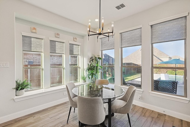 dining area with light hardwood / wood-style flooring, plenty of natural light, and a notable chandelier