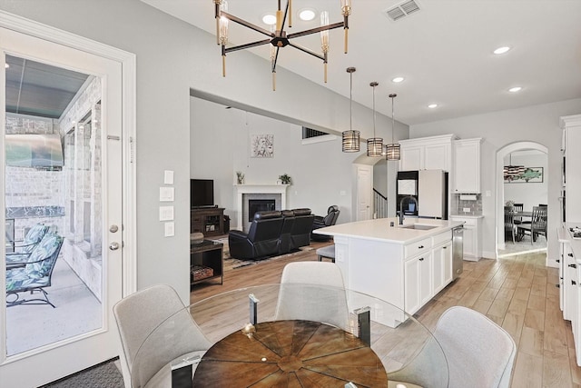 kitchen with pendant lighting, a notable chandelier, white cabinetry, and an island with sink