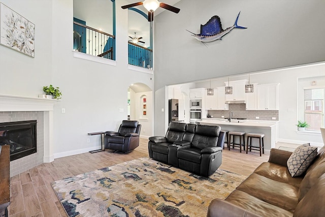 living room with a fireplace, a high ceiling, ceiling fan, and sink