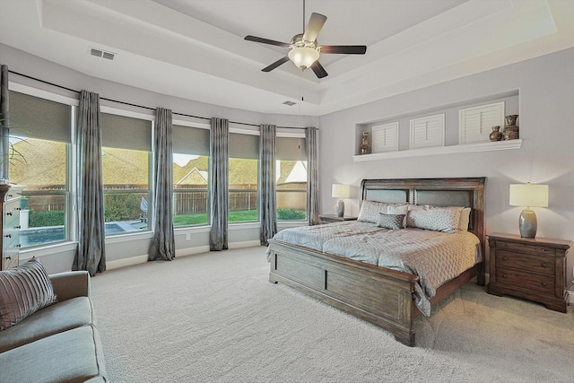 bedroom with ceiling fan, a raised ceiling, and light carpet