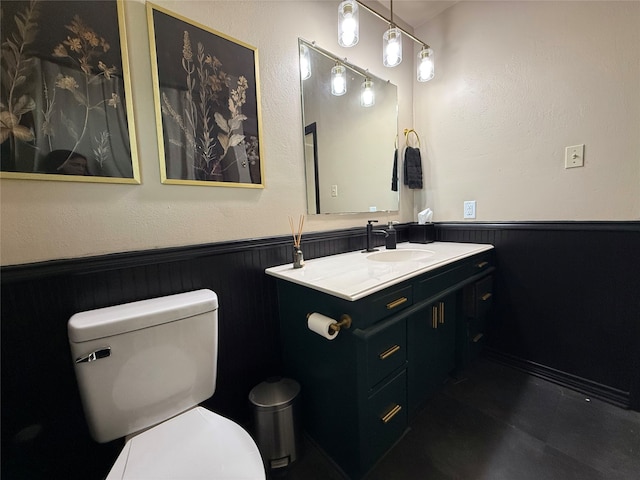 bathroom with vanity, toilet, and wooden walls