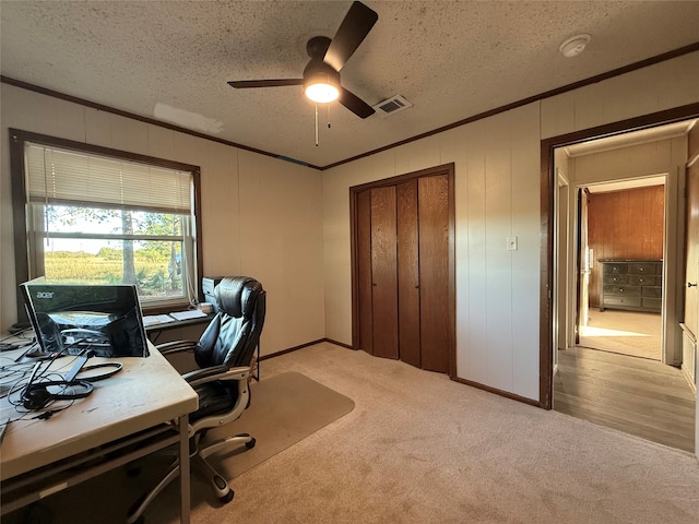 office with light carpet, a textured ceiling, ceiling fan, crown molding, and wood walls