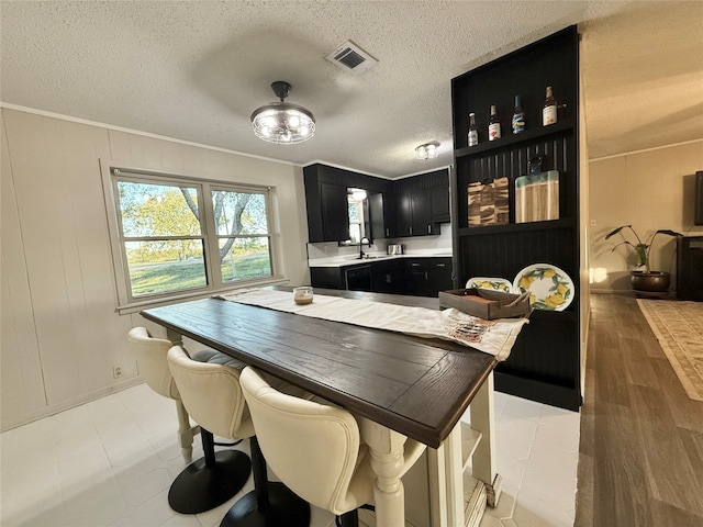 interior space featuring crown molding, sink, light hardwood / wood-style floors, and a textured ceiling