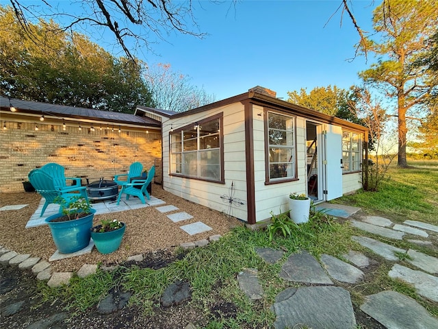 view of property exterior with a patio area and an outdoor fire pit