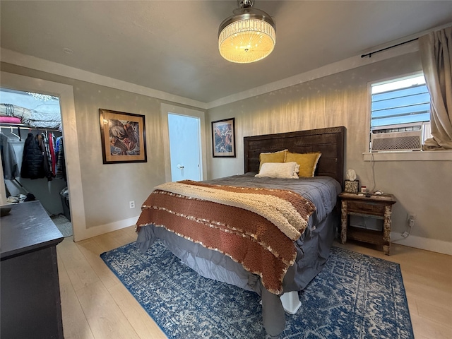 bedroom with a walk in closet, light hardwood / wood-style flooring, a closet, and cooling unit