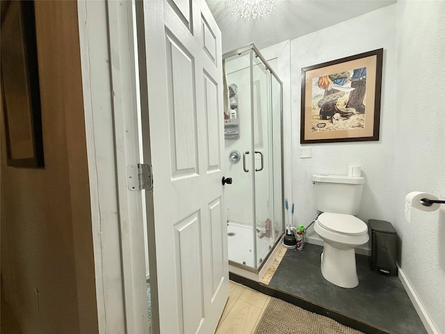 bathroom featuring a shower with door and toilet