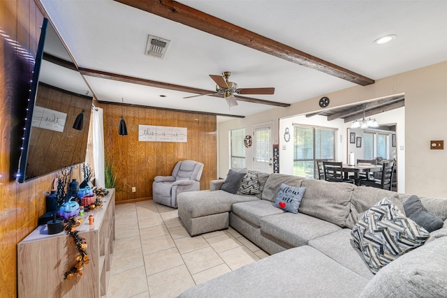 living room featuring wood walls, beamed ceiling, ceiling fan, and light tile patterned flooring