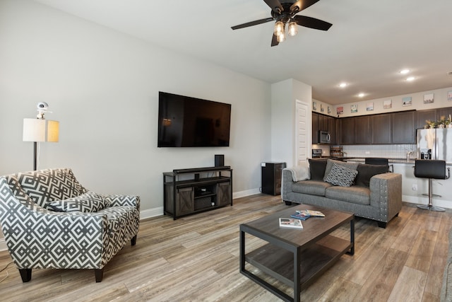 living room featuring sink, ceiling fan, and light hardwood / wood-style flooring