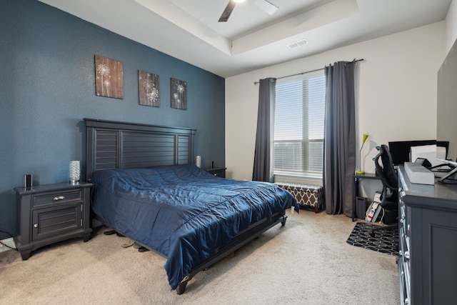 bedroom with ceiling fan, light carpet, and a raised ceiling