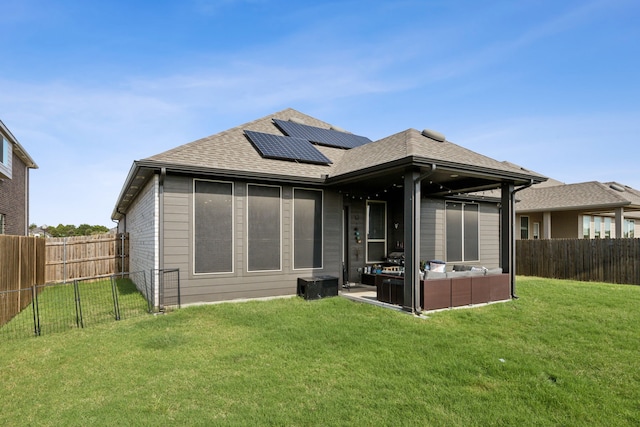 rear view of property featuring a lawn and solar panels