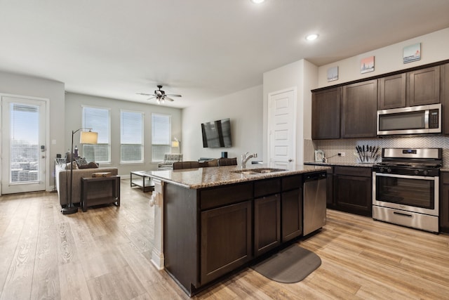 kitchen featuring light hardwood / wood-style floors, dark brown cabinetry, sink, a kitchen island with sink, and appliances with stainless steel finishes