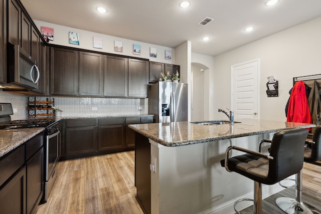 2277 Sheppards Ln, Waxahachie, TX 75167 - kitchen featuring stainless steel appliances, a sink, light wood-type flooring, arched walkways, and dark stone countertops