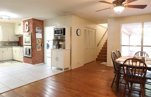 dining space with ceiling fan, wooden walls, light hardwood / wood-style floors, and washer / dryer