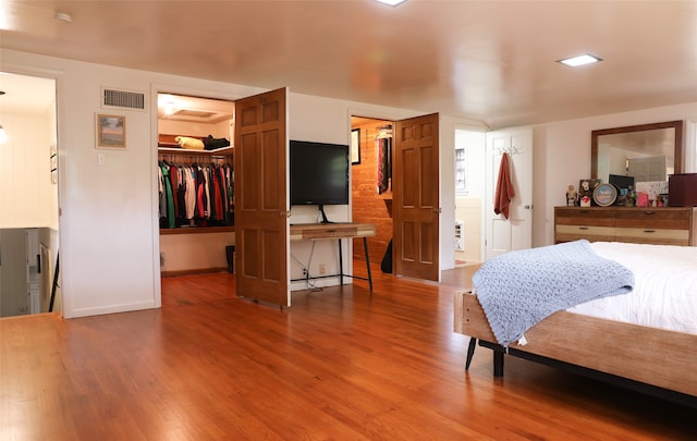 bedroom featuring hardwood / wood-style floors, ensuite bath, a walk in closet, and a closet