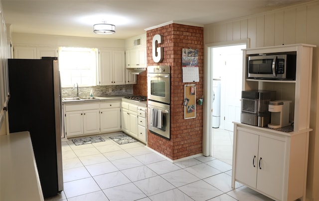 kitchen with backsplash, white cabinets, sink, and stainless steel appliances