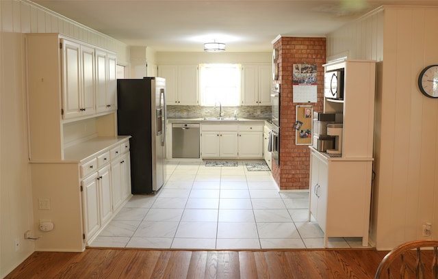 kitchen featuring stainless steel appliances, wood walls, light hardwood / wood-style floors, and tasteful backsplash