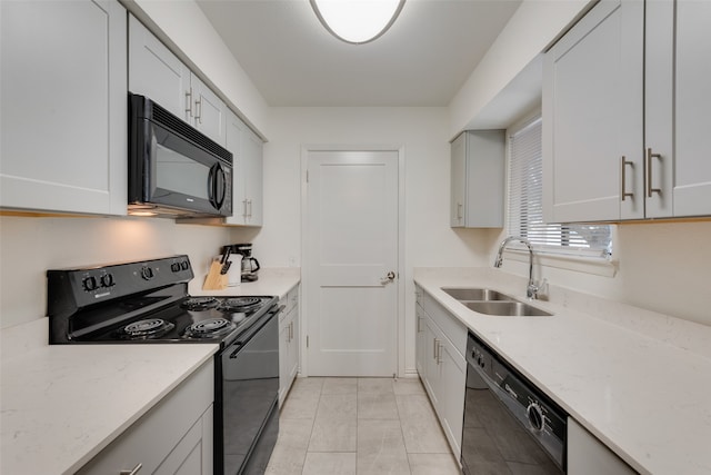 kitchen with light stone countertops, white cabinetry, sink, and black appliances