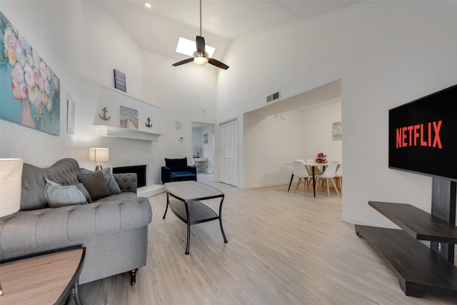 living room with high vaulted ceiling, light hardwood / wood-style flooring, and ceiling fan