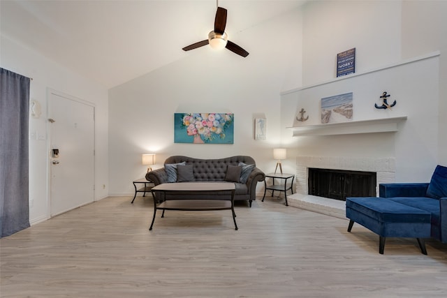 living room with a brick fireplace, high vaulted ceiling, light hardwood / wood-style floors, and ceiling fan